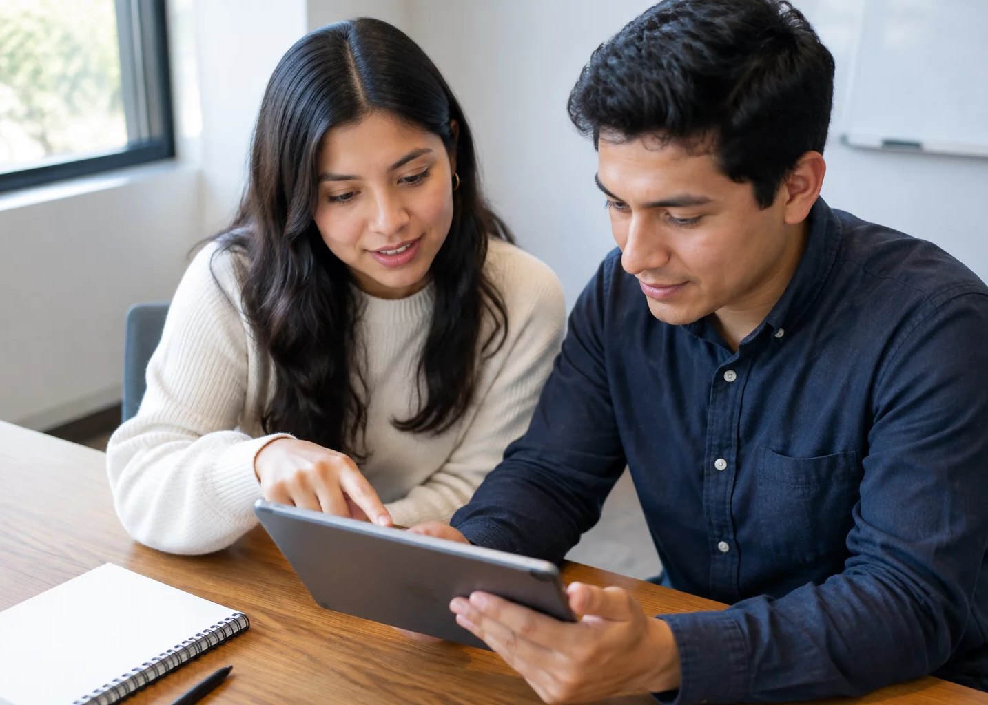 Dos personas inclinadas sobre una tablet con anotaciones